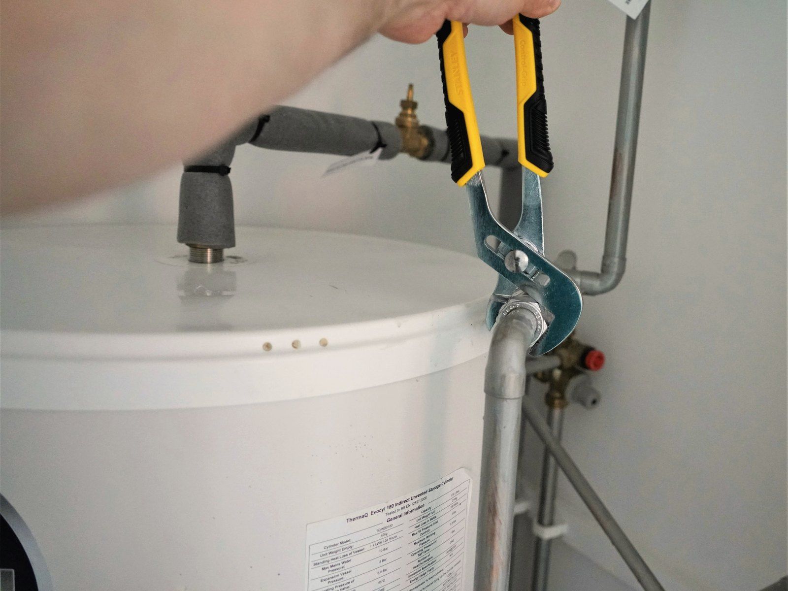 A plumber tightening a fitting on a tank water heater