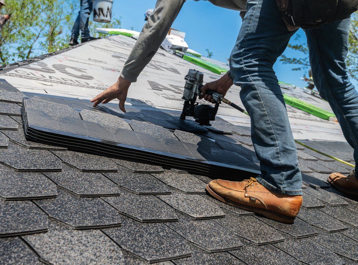 A roofer nailing new architectural shingles