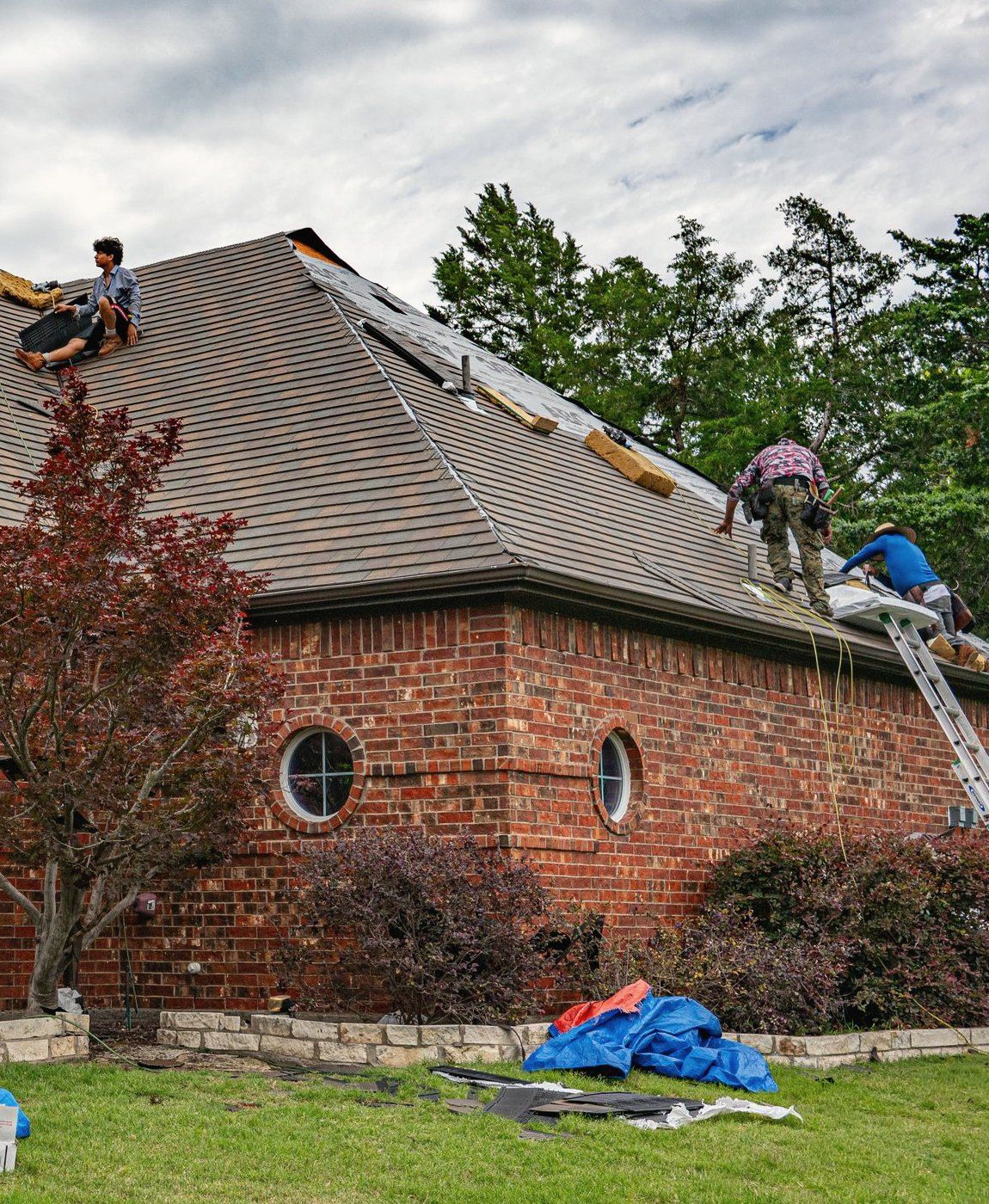 A crew re-roofing a brick two-story house